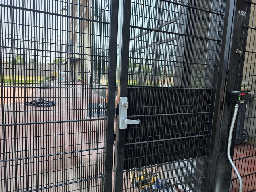 Commercial exit lever trim with keyed cylinder on a security gate
