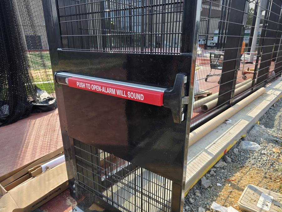 Detex alarmed panic bar on a security fence gate